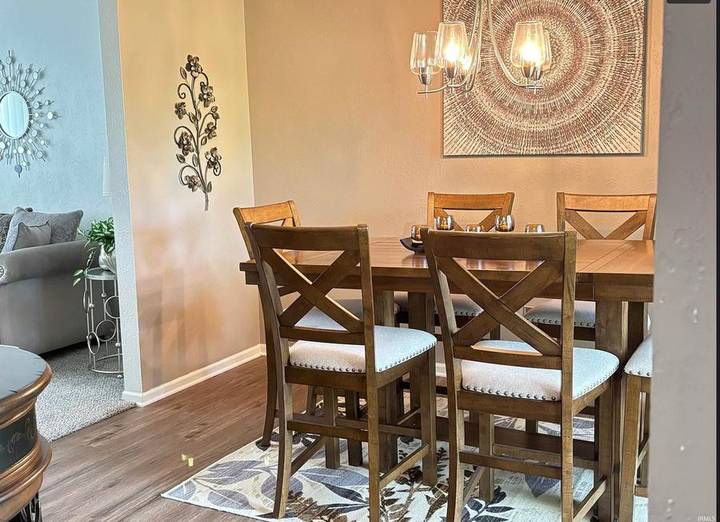 Original listing photo of the dining room: wooden table and six chairs under a chandelier
