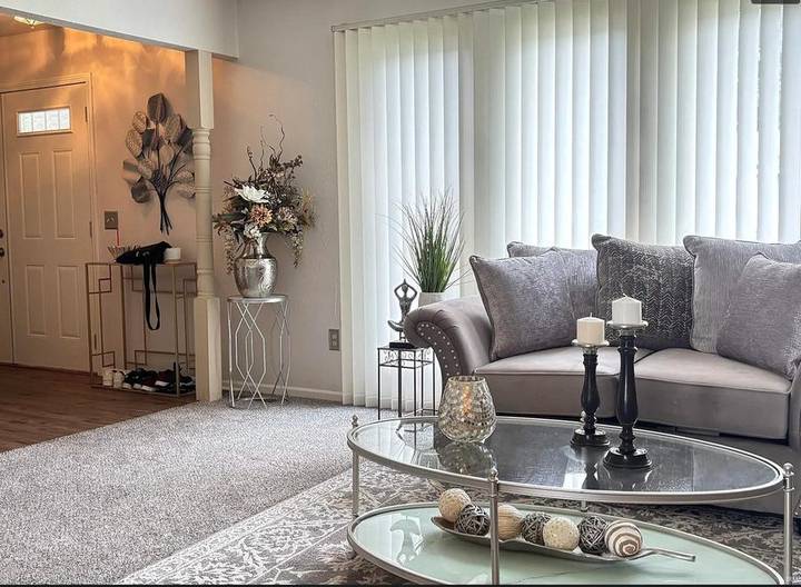 Original listing photo of the entry and living room, with shoes and bags beside the front door