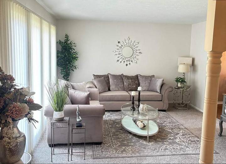 Original listing photo of the living room: grey sofa, glass coffee table and a patterned rug