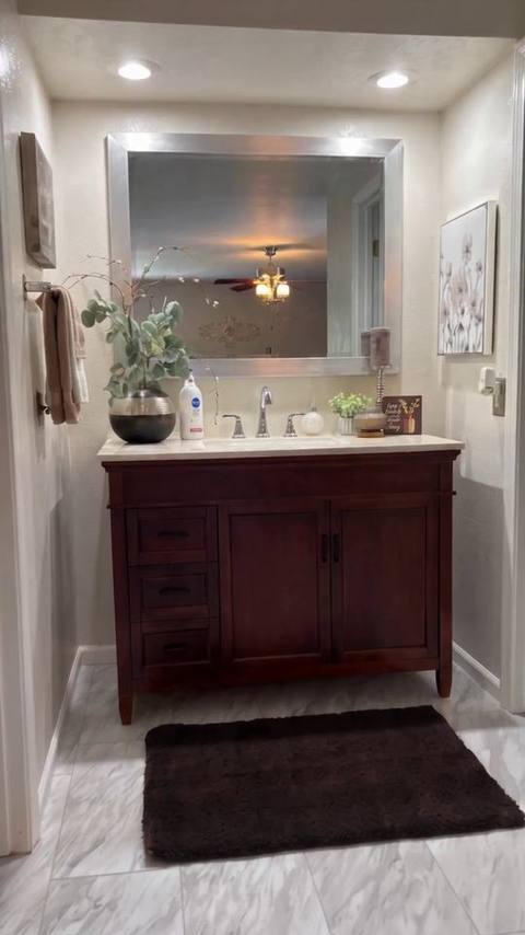 Vertical frame from the reel: the same primary bathroom vanity and tile floor with the scale removed