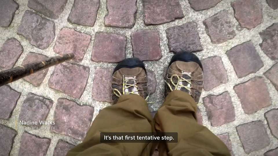 Looking down at a pilgrim's boots on wet cobblestones, subtitle: It's that first tentative step.