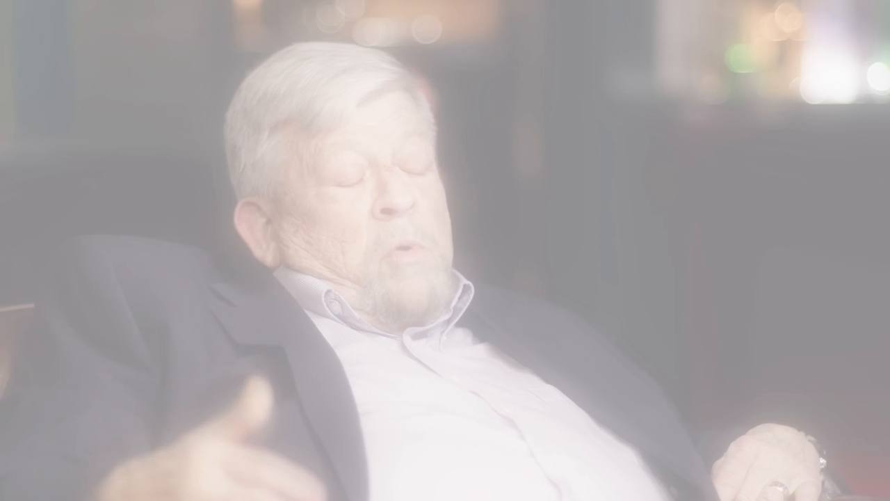 Joe McMoneagle mid-interview, lit by the white-light bloom effect built from his own shot